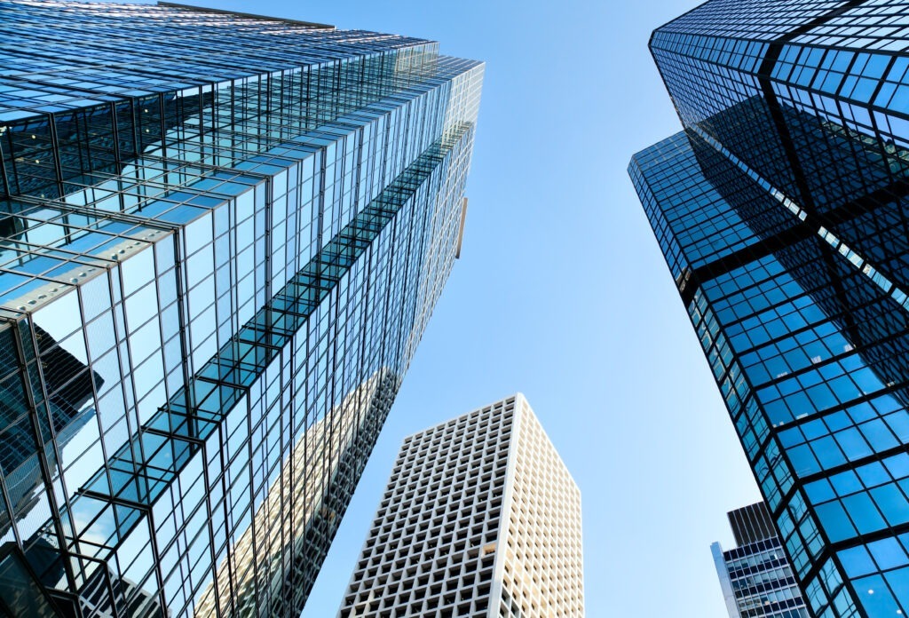 Four tall glass office buildings in a downtown setting, seen from the ground up, toward a blue sky. This represents our expertise in networking software systems. Enterprise software integration is our niche.