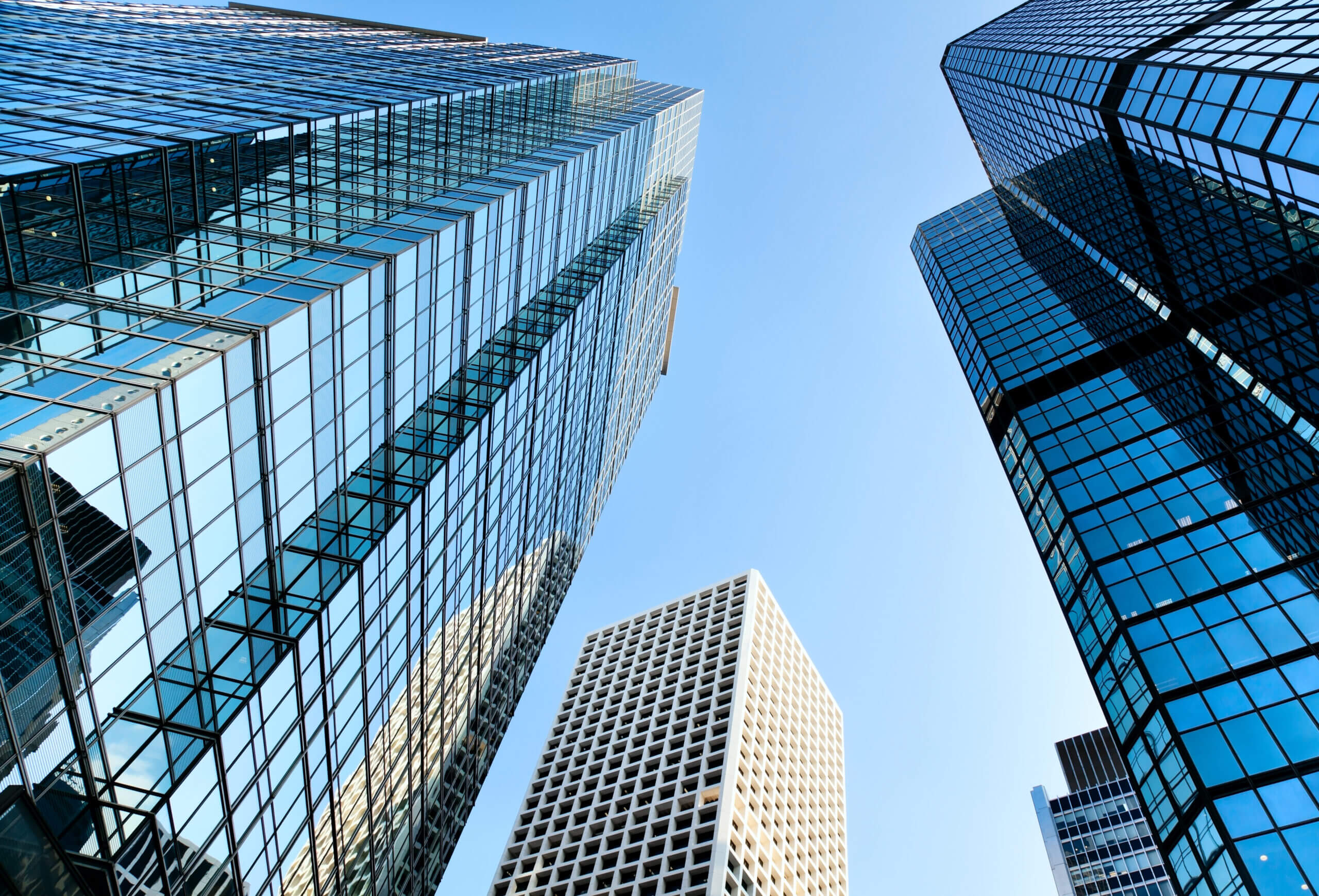 Four tall glass office buildings in a downtown setting, seen from the ground up, toward a blue sky. This represents our expertise in networking software systems. Enterprise software integration is our niche.